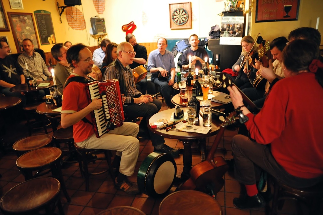 Musicians playing traditional folk instruments like accordion and violin in a cozy British pub, with patrons enjoying beers.
